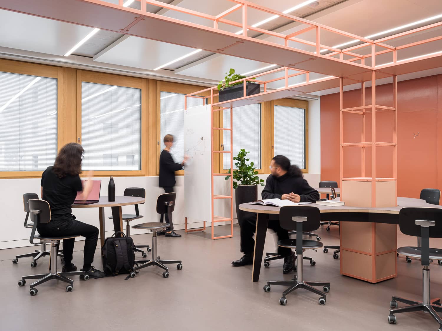 In einem grossen, multifunktionalen Raum arbeiten drei Personen gemeinsam an einem Projekt